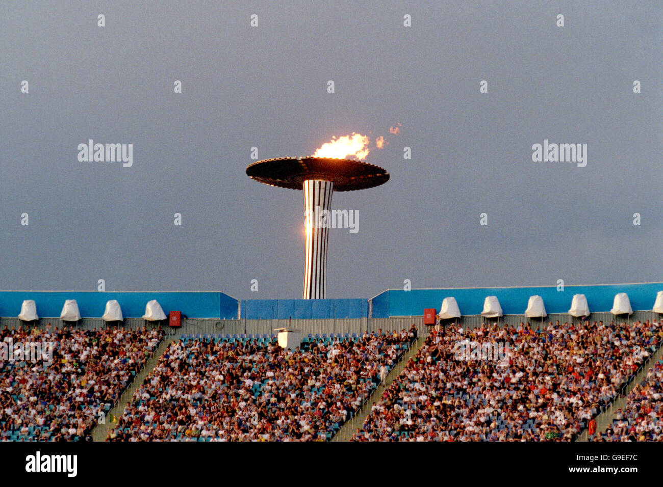 Olympische Spiele 2000 In Sydney - Leichtathletik. Die Olympische Flamme brennt hoch über dem Stadion Australia Stockfoto