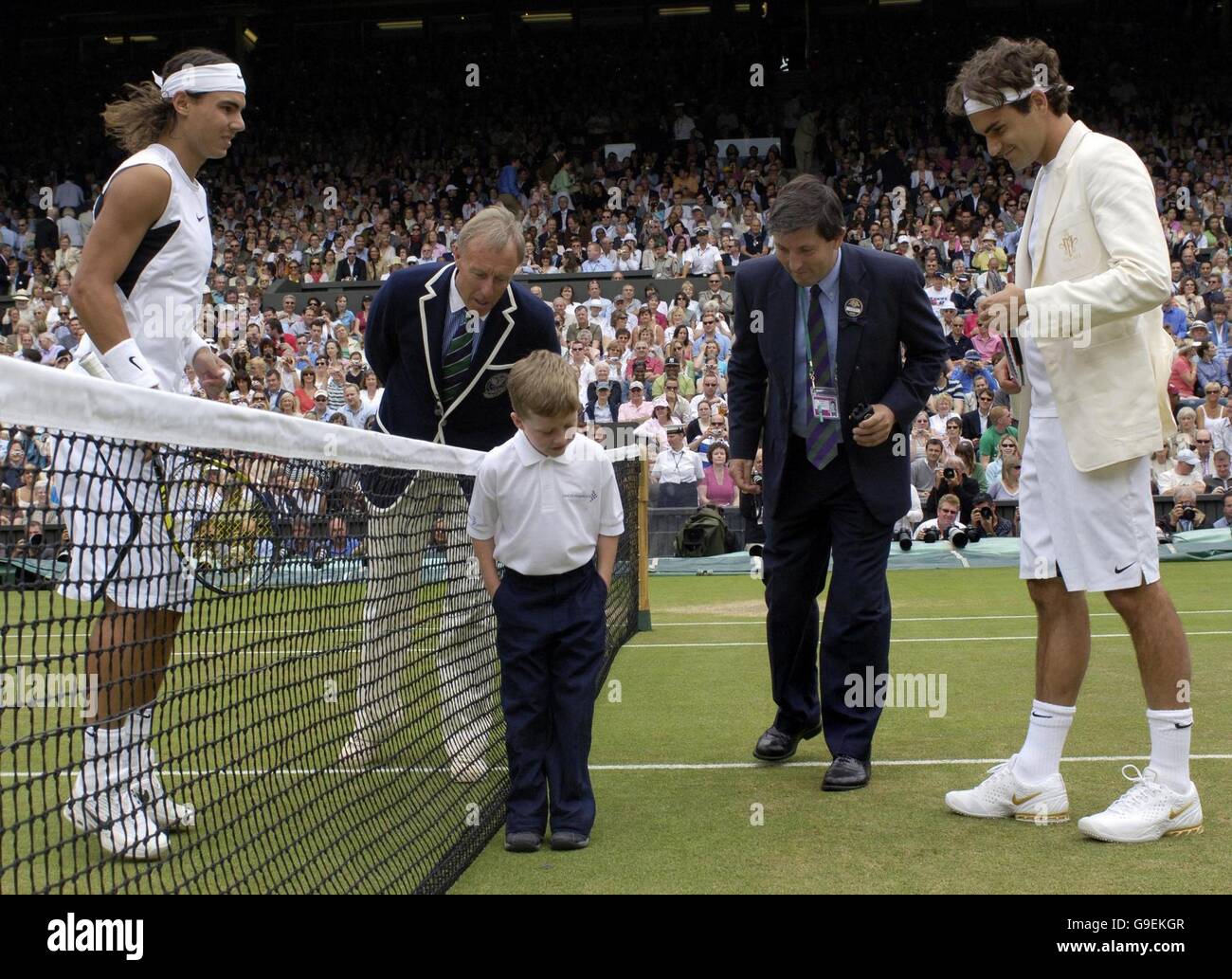 William Caines, sieben Jahre alt, aus Beckenham, Kent, vertritt Cancer Research UK, als er den Münzwurf vor dem Männer-Einzel-Finale zwischen dem Schweizer Roger Federer (rechts) und dem spanischen Rafael Nadal (links) während der All England Lawn Tennis Championships in Wimbledon vorführt. Stockfoto