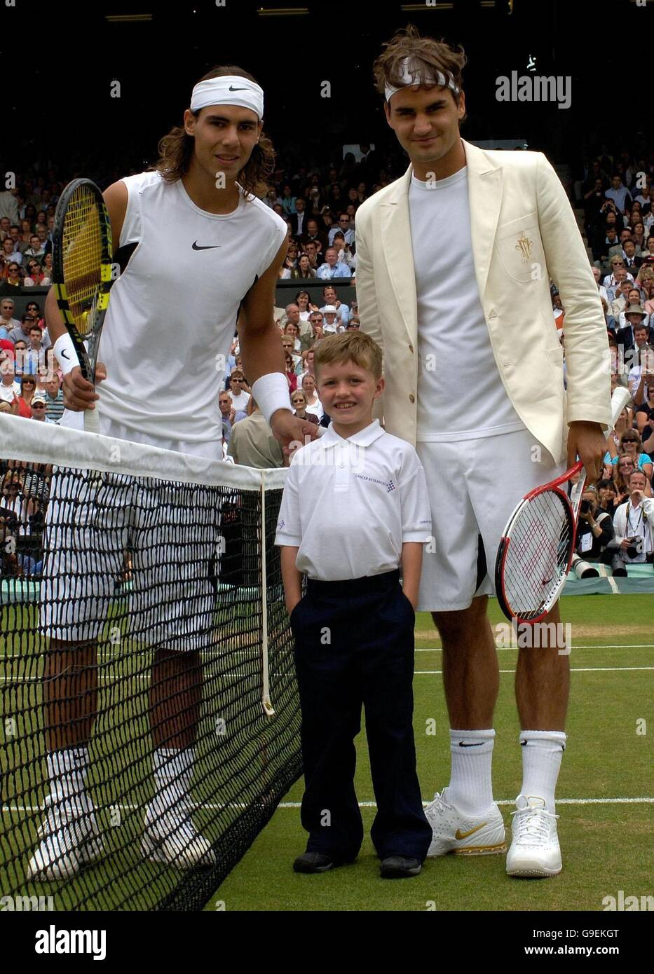 William Caines, sieben Jahre alt, aus Beckenham, Kent, vertritt Cancer Research UK, posiert mit dem Schweizer Roger Federer (rechts) und dem spanischen Rafael Nadal (links), nachdem er den Münzwurf vor dem Finale der Männer-Singles bei den All England Lawn Tennis Championships in Wimbledon gemacht hat. Stockfoto