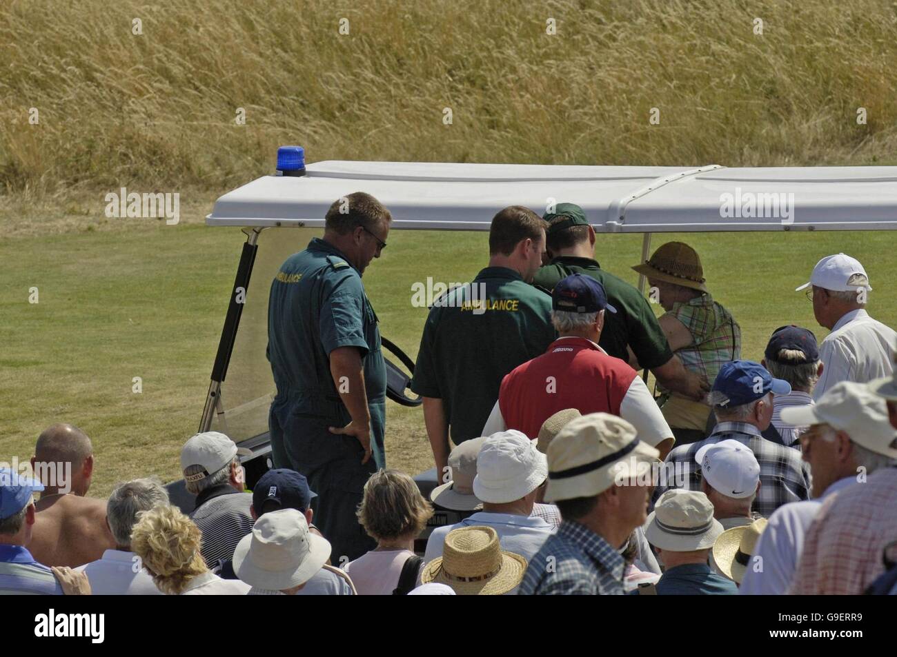 Ein Zuschauer wird von Krankenwagen-Mitarbeitern nach Ohnmacht in der Hitze auf dem Platz im Royal Liverpool Golf Club, Hoylake, während der Übungsrunden zu einem Buggy gebracht. Die 135. Open Championship startet am Donnerstag auf dem Platz. Stockfoto