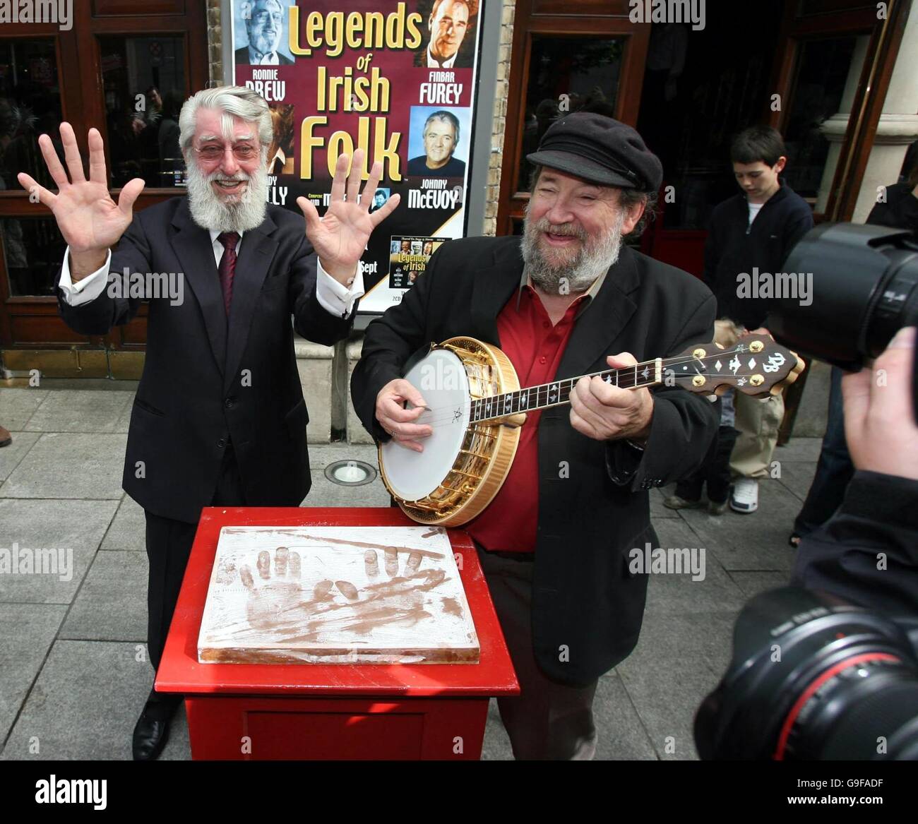 Dubliners Frontmann Ronnie Drew (links) wird von Dubliner Barney McKenna am Banjo unterhalten, nachdem er seine Hände im Gaiety Theatre in Dublin in Gips gesetzt hatte. Stockfoto