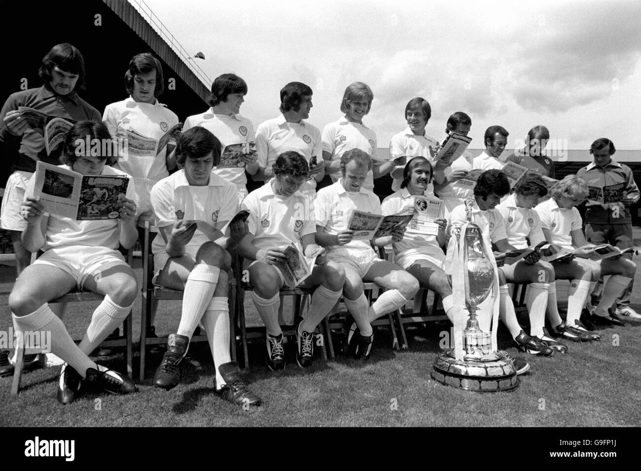 Das Leeds United Team las Kopien des Leeds United Matchday Programms, während sie warten, bis ein Gruppenbild mit dem League Championship Pokal gemacht wurde Stockfoto