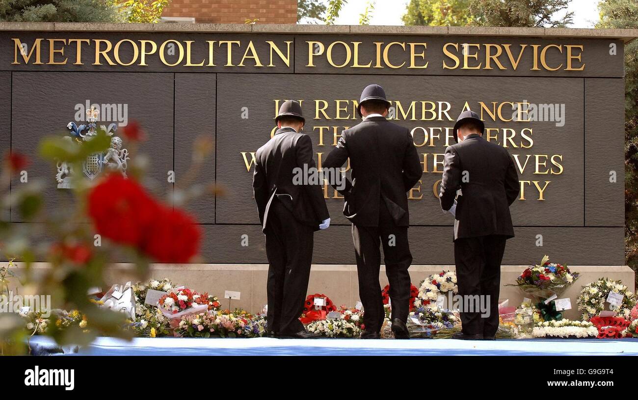 Eine Gruppe von drei Polizeibeamten untersucht die floralen Ehrungen, die nach dem jährlichen Metropolitan Police Memorial Day-Gottesdienst am Police Training College in Hendon North West London am Memorial Stone gelegt wurden. Stockfoto