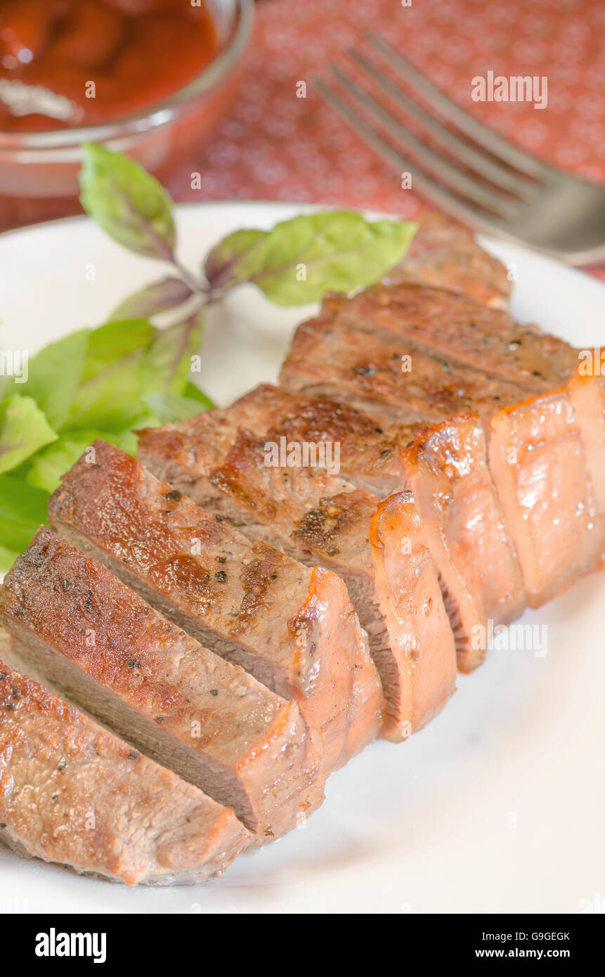 Gegrilltes Rindersteak mit Salat und Sauce auf Holztisch im weißen Teller. Stockfoto