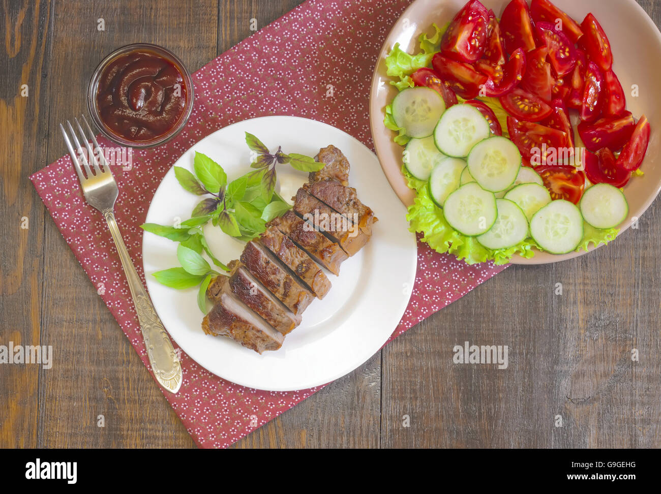 Gegrilltes Rindersteak mit Salat und Sauce auf Holztisch im weißen Teller. Stockfoto