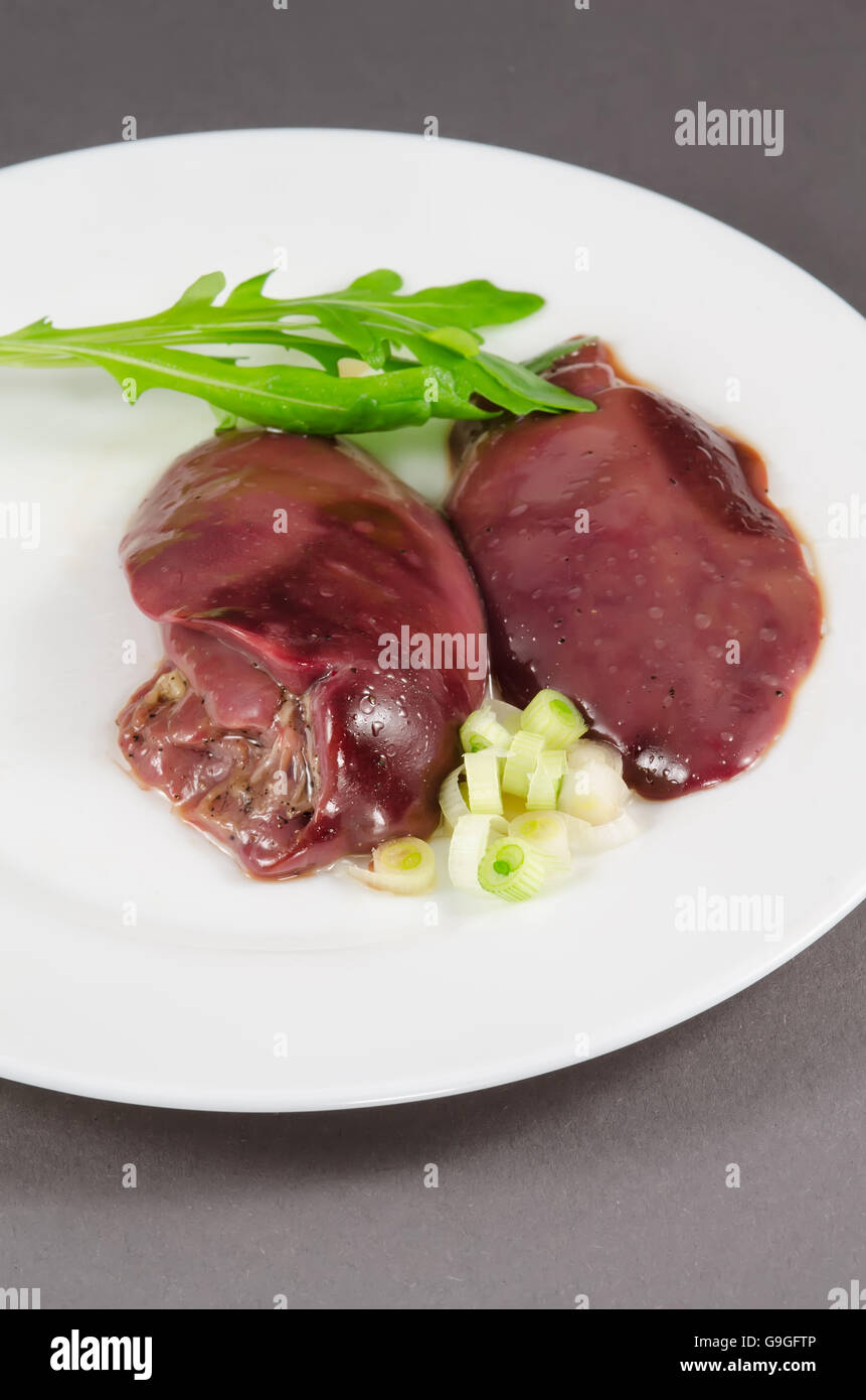 Rohe Hühnerleber mit Gemüse im weißen Teller Stockfoto