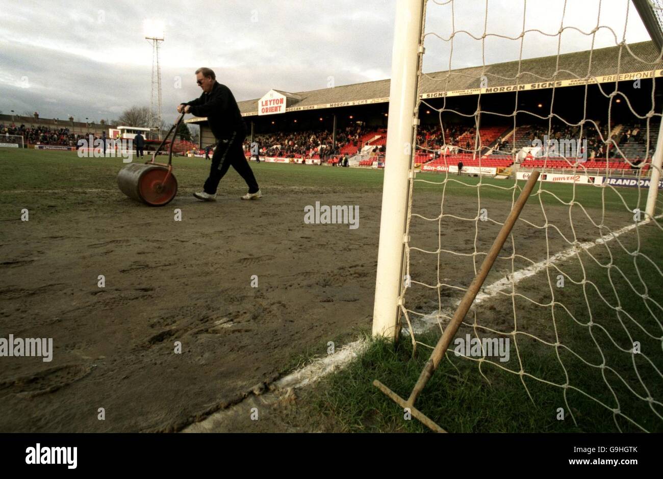 Der Leyton Orient-Platzwart Charlie Hasler nutzt während der Halbzeitpause eine altmodische Rolle auf dem schmutzigen, schlammigen Platz auf der Brisbane Road. Er ist zu einer umstrittenen Figur geworden, da er nur den Strafraum vor das Tor rollt, das Orient in der zweiten Hälfte angreift Stockfoto