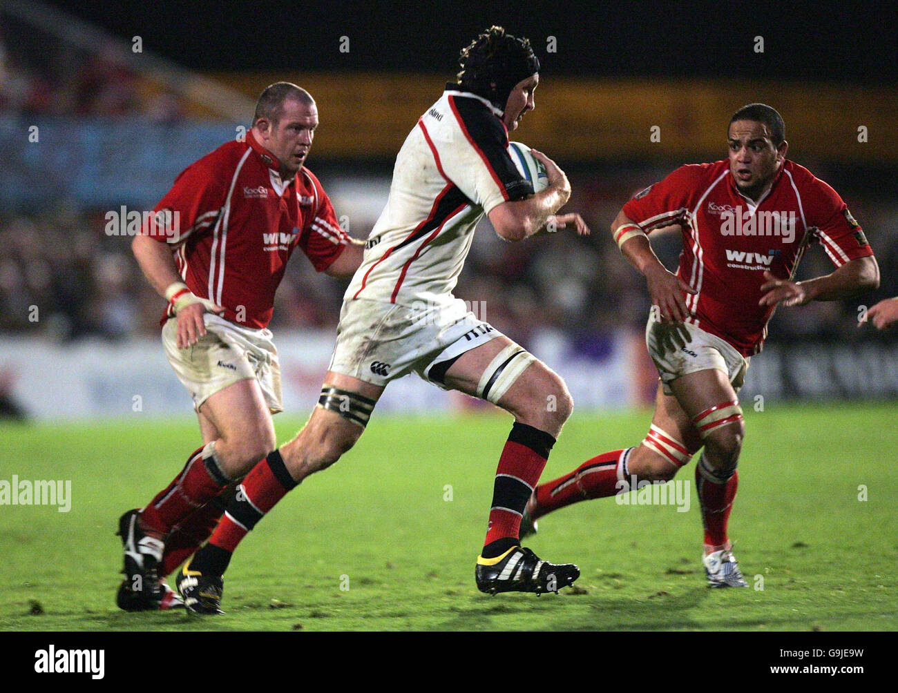 Rugby Union - Heineken Cup Pool Five - Llanelli gegen Ulster - Stradey Park. Ulsters Justin Harrison (Mitte) wird während des Heineken Cup, dem Spiel am 5. Pool im Stradey Park, Llanelli, an der Llanelli-Verteidigung vorbeigeschlemmt. Stockfoto