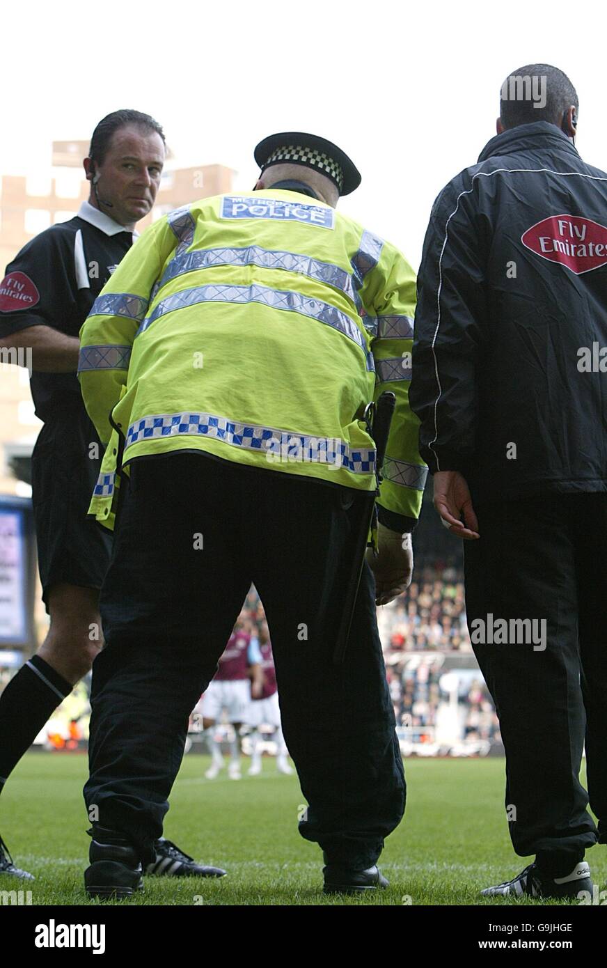 Fußball - FA Barclays Premiership - West Ham United / Arsenal - Upton Park. Ein Polizeibeamter wählt das Objekt, das aus der Menge geworfen wurde, und trifft auf Robin van Persie von Arsenal Stockfoto