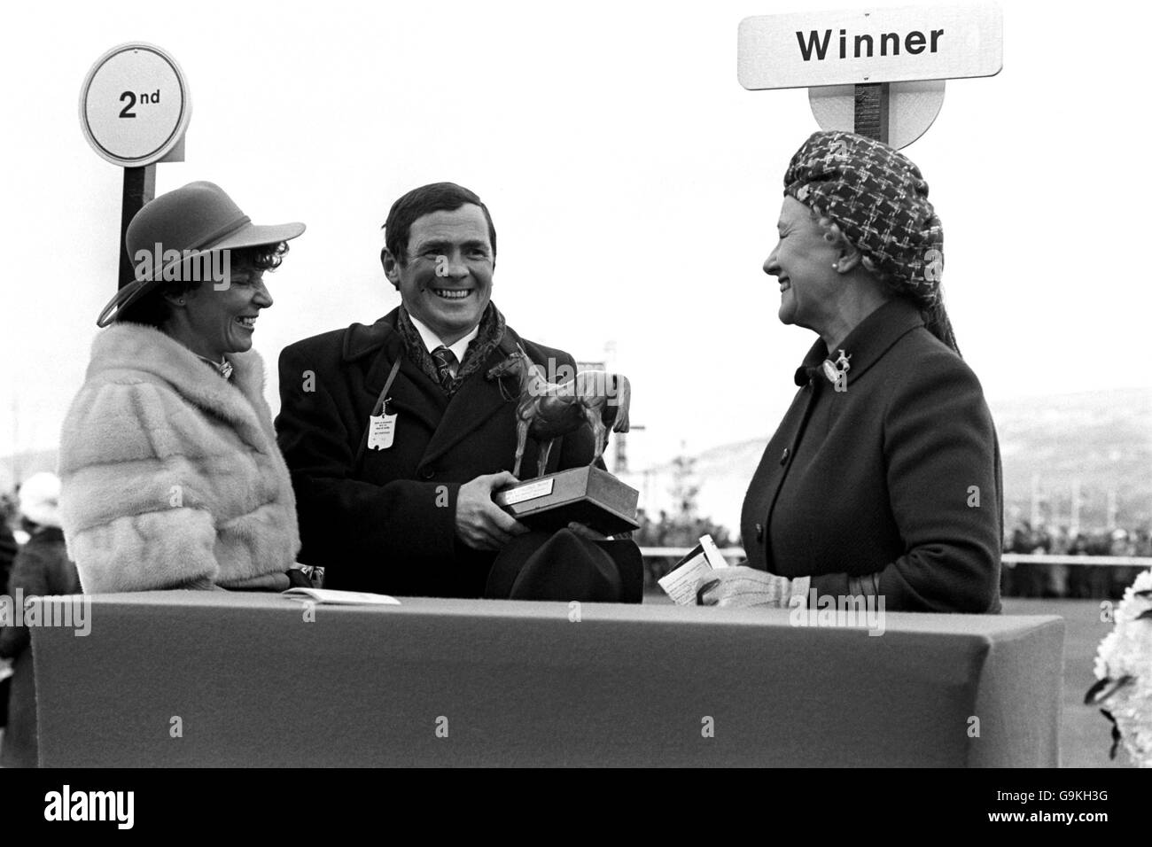 Besitzer T.J. Murray (c) und seine Frau (l) erhalten die Arkle Challenge Trophy von der Herzogin von Westminster (r), nachdem sein Pferd Brockshee das Rennen gewonnen hat Stockfoto
