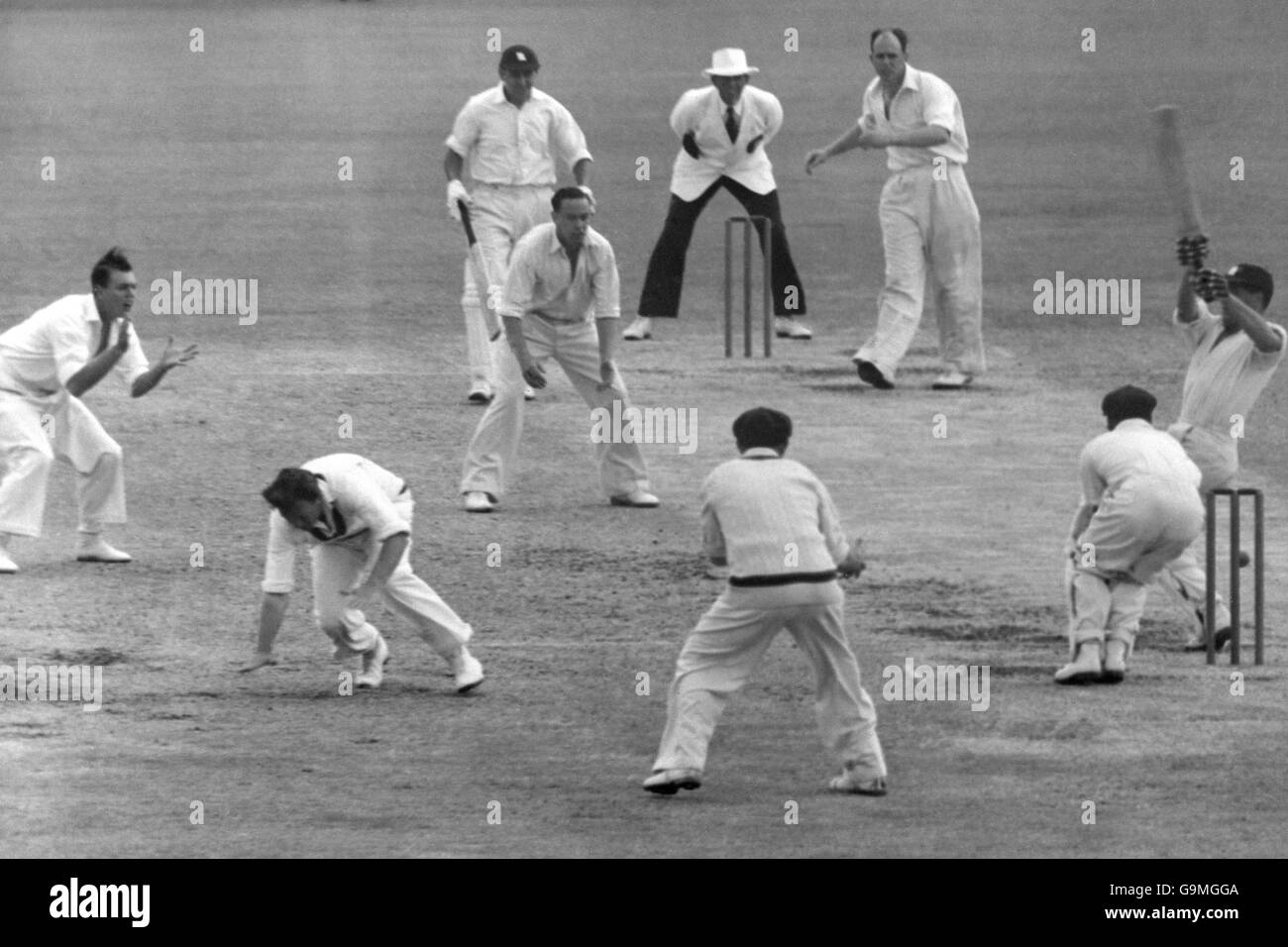Cricket - The Ashes - erster Test - Australien - England - The Gabba - Fünfter Tag. Richie Benaud (zweite l) in Australien nimmt Ausweichmanöver an, während Trevor Bailey (r) in England versucht, Ian Johnson (dritte r) einen Ball zu fegen Stockfoto