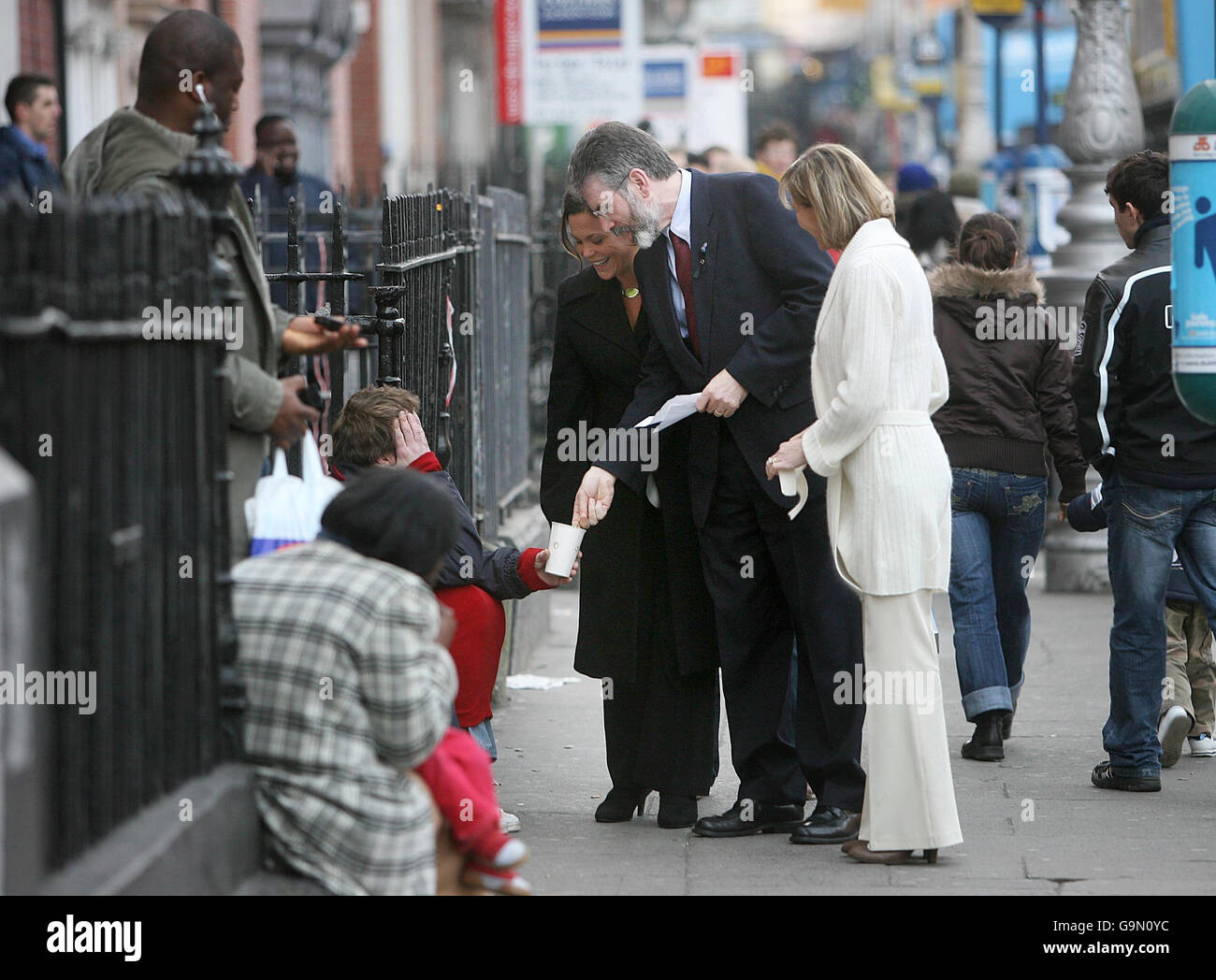 Gerry Adams gibt einer Bettlerin am Parnell Square in Dublin eine Abwechslung, neben Mary Lou McDonald und Martina Anderson (in weiß). Stockfoto