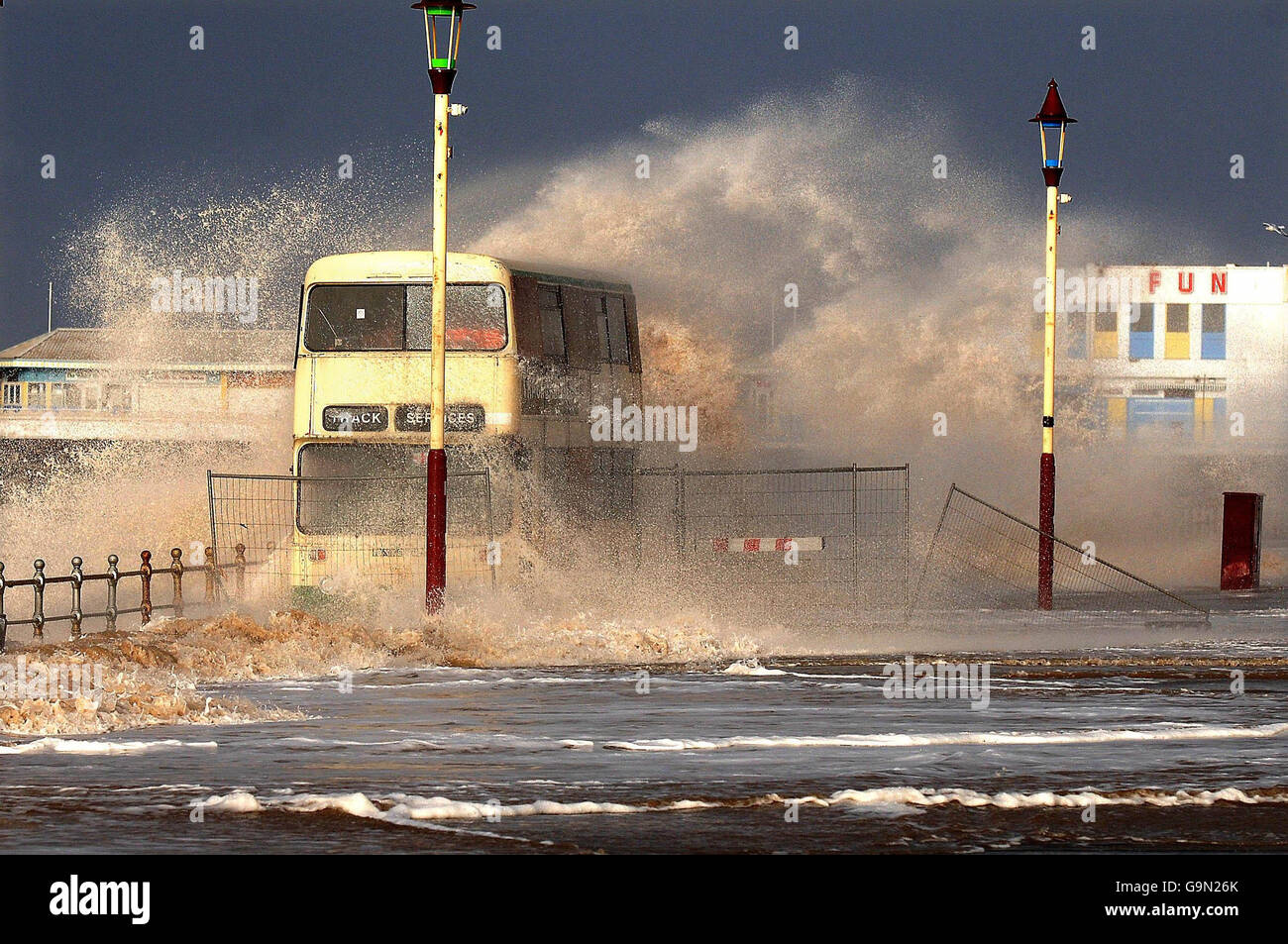 Ein Bus auf der Blackpool Promenade wird von einer Welle umschlungen, während Sturmwind und hohe See die Westküste Englands umschlingen. Stockfoto