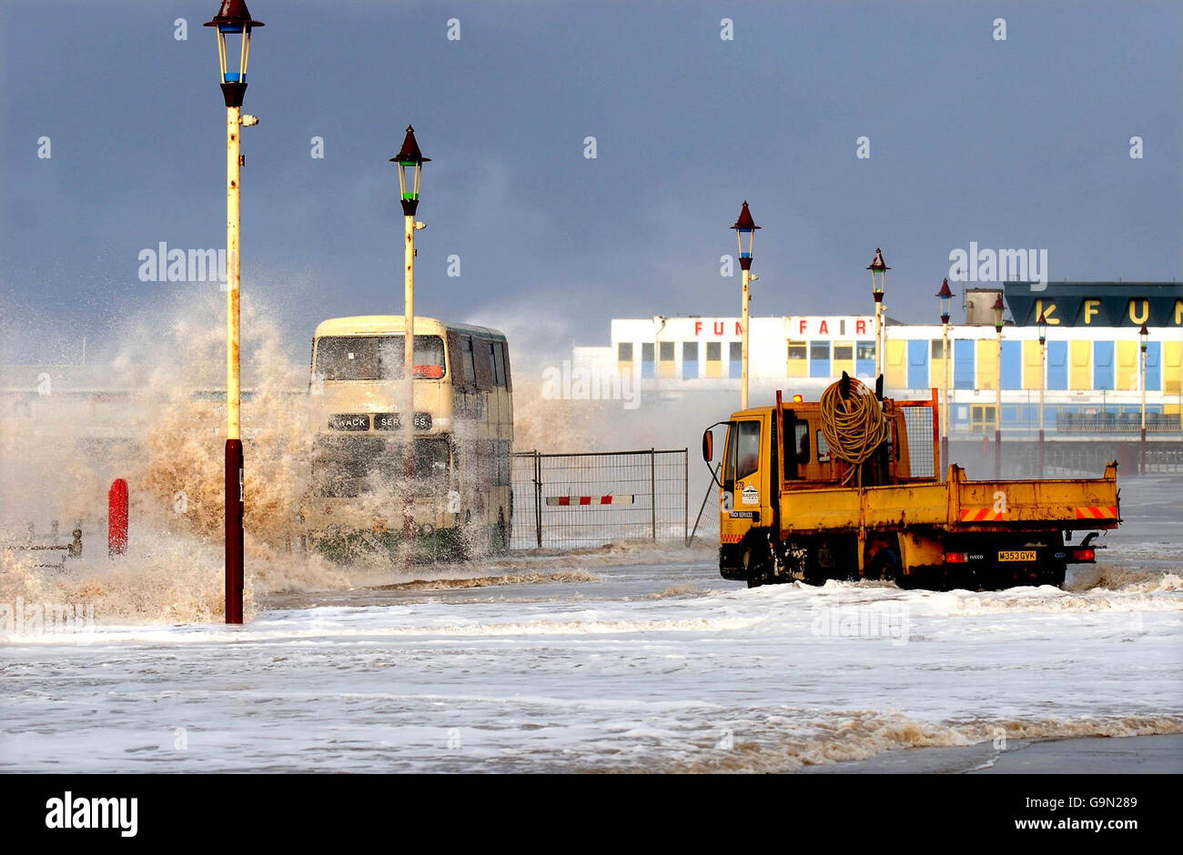 Ein Lastwagen parkt neben einem Bus an der Blackpool Promenade, um gestrandeten Arbeitern zu helfen, da der Bus von einer Welle überschwemmt wird, während Sturmwinde und hohe See die Westküste Englands überschwemmen. Stockfoto