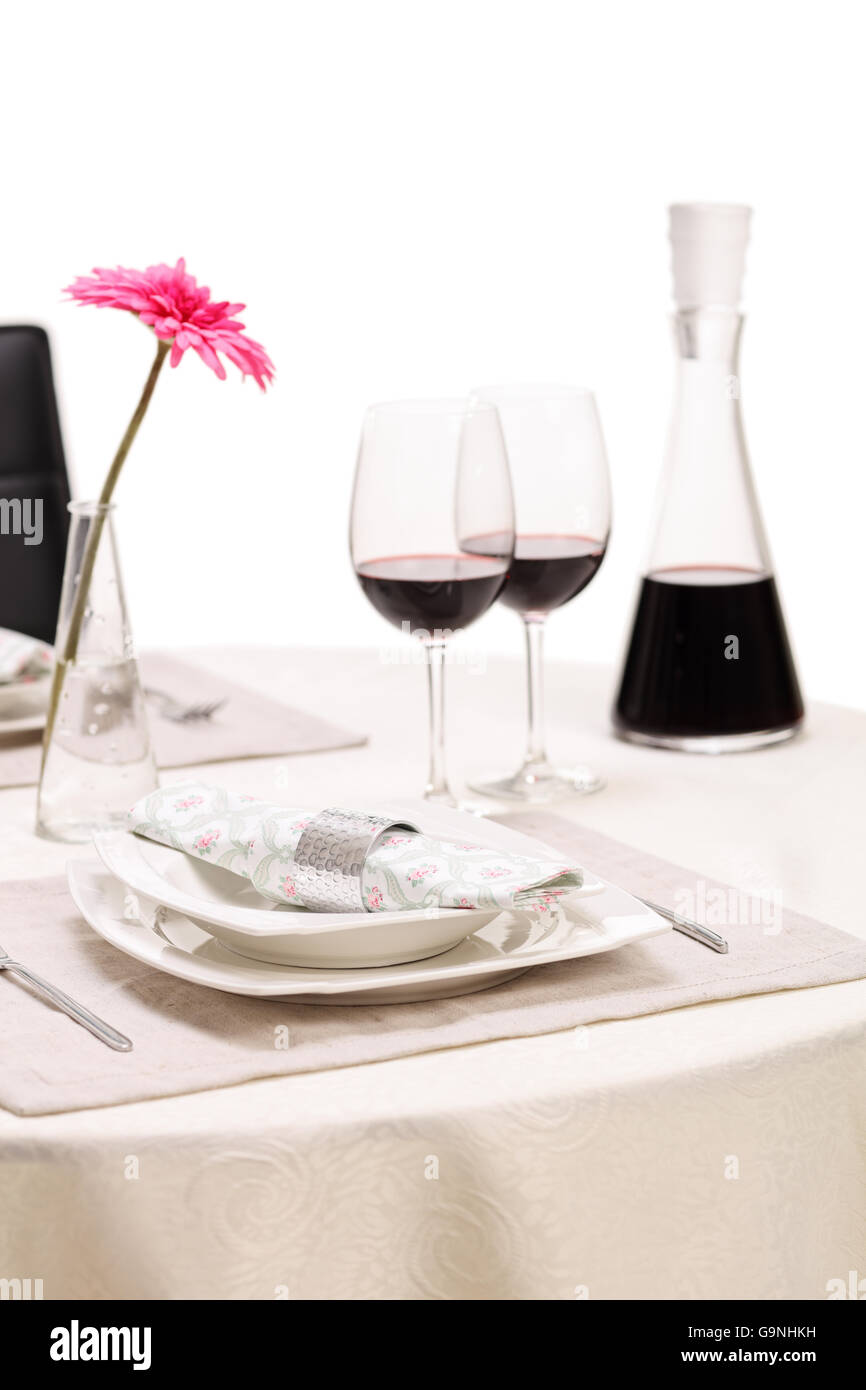 Vertikale Schuss von einem romantischen Esstisch mit zwei Gläser Rotwein und eine Blume isoliert auf weißem Hintergrund Stockfoto