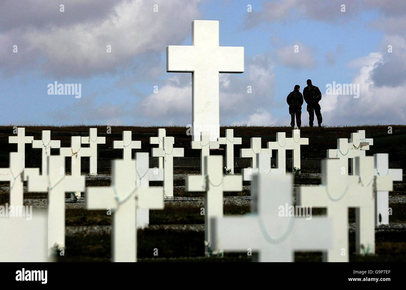 Zwei Mitglieder der britischen Armee blicken über Goose Green neben einem Denkmal für alle argentinischen Soldaten, die während des Falklandkrieges getötet wurden. Stockfoto