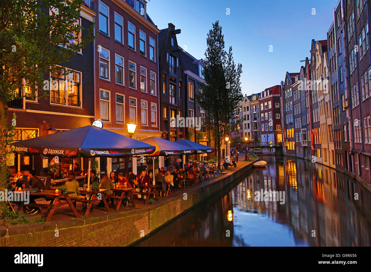 Häuser und Restaurants am Oudezijds Achterburgwal Kanal bei Sonnenuntergang in Amsterdam, Holland Stockfoto