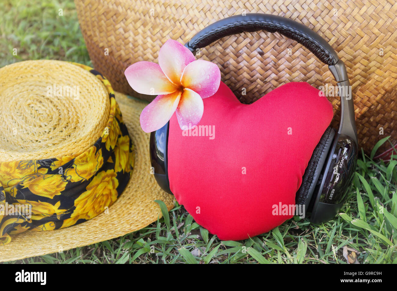 Rotes Herz hören Sie Musik über Kopfhörer mit rosa Blume Frangipani oder Plumeria und Sommer Hut und Tasche im Hintergrund mit Entspannung Stockfoto