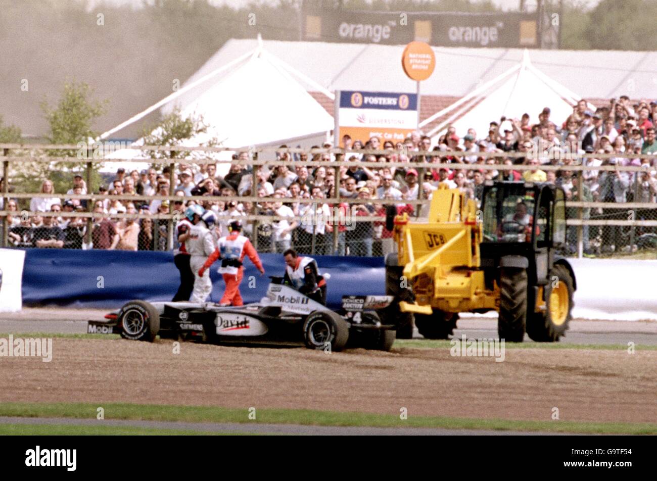 David Coulthard wird von Marschalls geführt, nachdem er mit Jordans Jarno Trulli kollidierte, was dazu führte, dass er aus dem Rennen auszog. Stockfoto