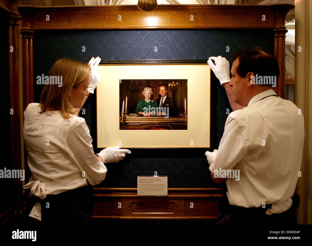 Ausstellungsassistenten hängen ein aktuelles Porträt von Königin Elizabeth II. Und Prinz Philip in einer Ausstellung im Schloss Windsor, in der Grafschaft von England. Stockfoto