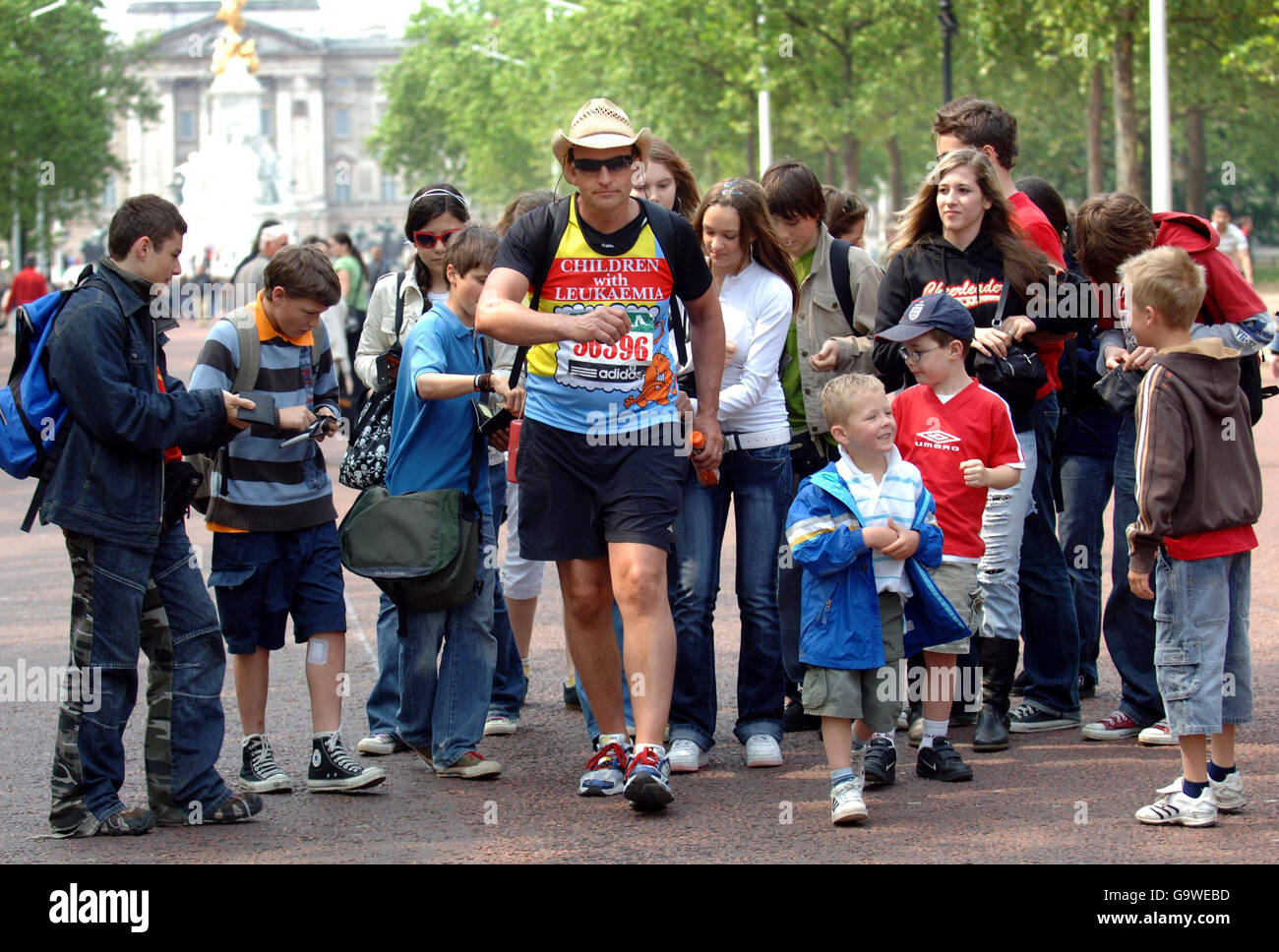 Zeitlupenläufer Greg Billingham, 39, der Geld für Kinder mit Leukämie aufbringt, beendet den London Marathon in der Mall eine Woche nach der Veranstaltung selbst. Er ist umgeben von Wellwishers, die Münzen in zwei Sammelboxen legen, die an seine Taille geschnallt sind Stockfoto
