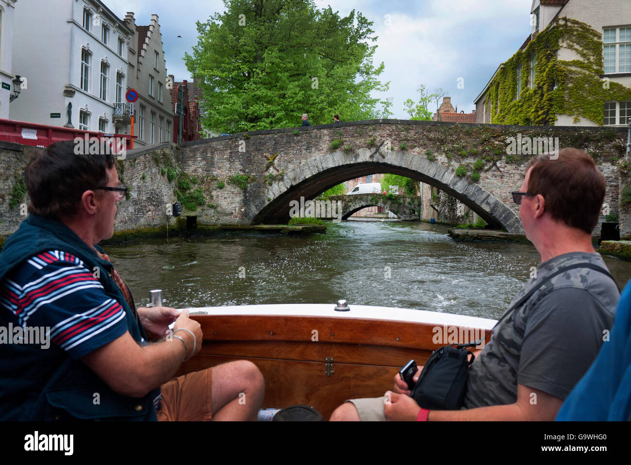 Touristen genießen eine Bootsfahrt auf den Kanälen von Brügge in Belgien. Stockfoto