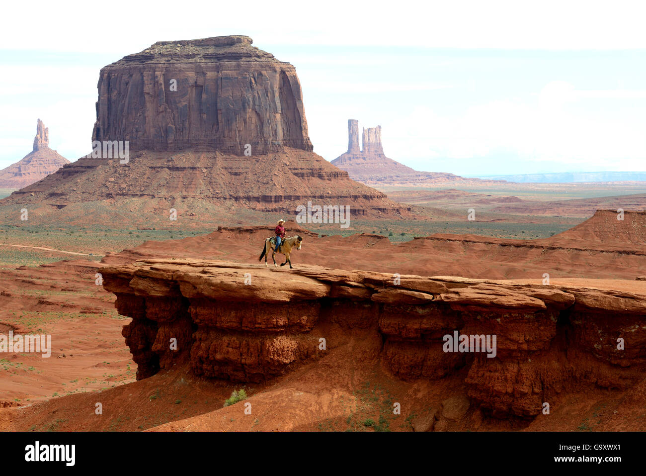 Navajo Mann Reitpferd vor Felsformationen des Monument Valley, Utah, USA, Mai 2014. Stockfoto