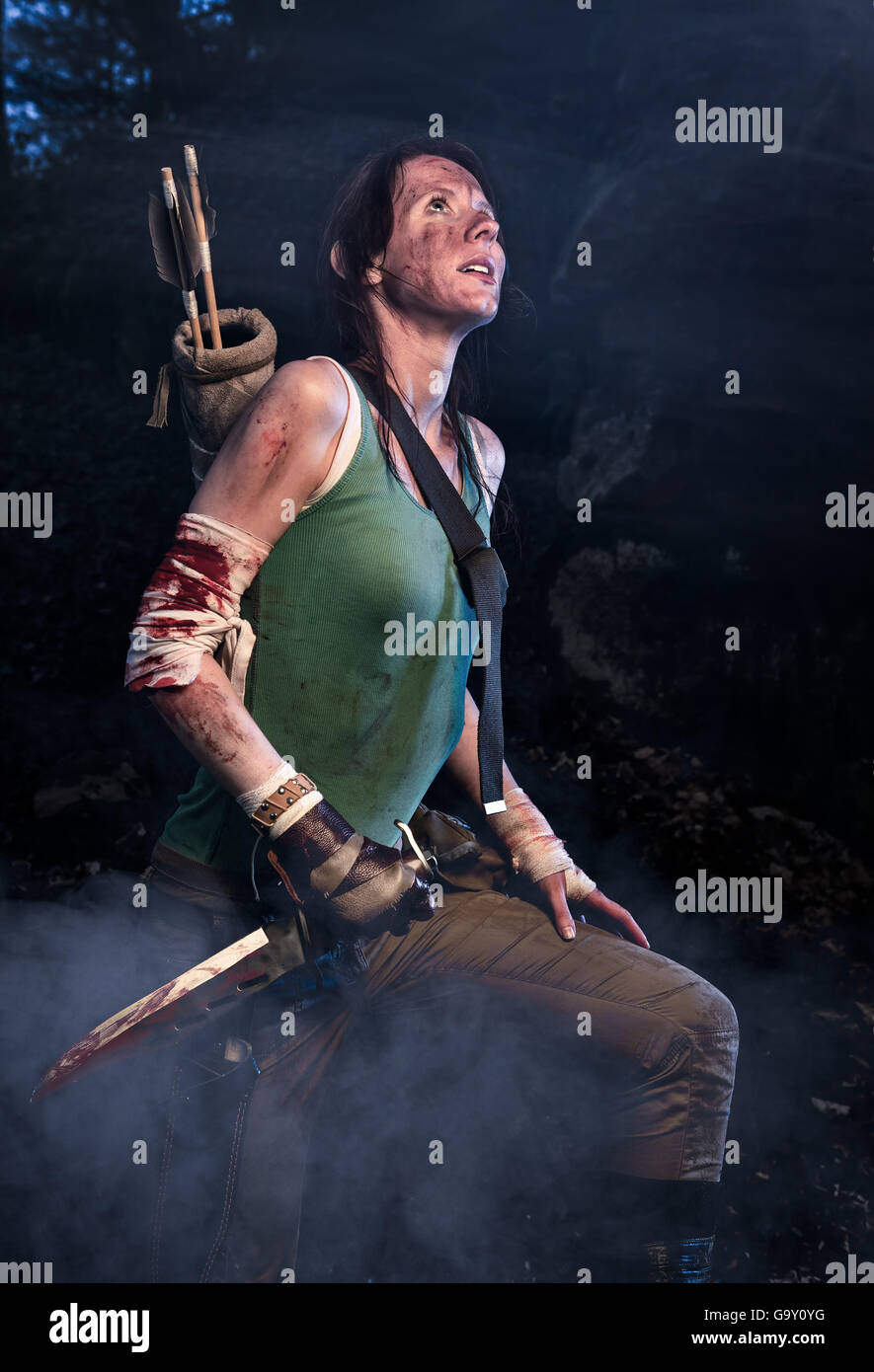 Rise of the Tomb Raider. Frau verkleidet als Lara Croft steht neben den Höhlen, ein Messer in der Hand hält. Stockfoto