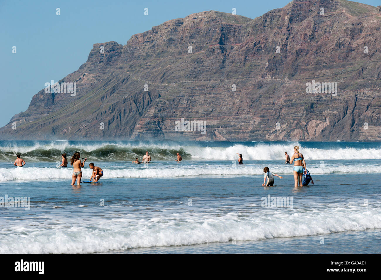 Touristen im Wasser, am Strand Playa de Famara, La Caleta de Famara, Westküste von Lanzarote, Kanarische Inseln, Spanien, Europa Stockfoto