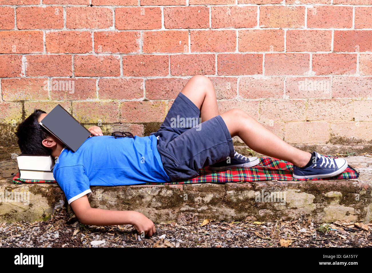 Teenager liest entspannt Buch im Hintergrund des roten Backsteinmauer. leeren Raum für Text. Stockfoto