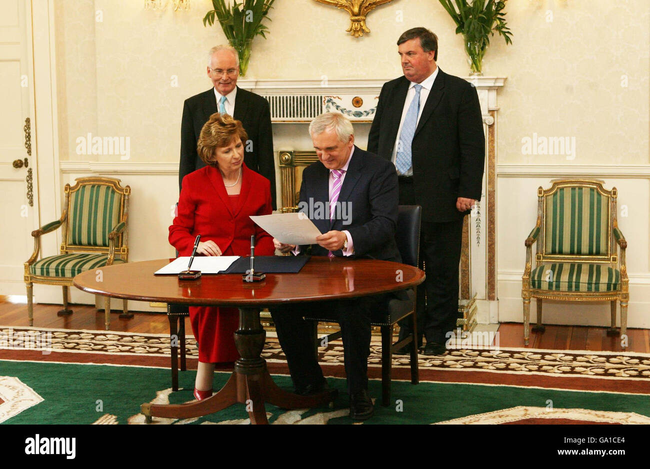 Taoiseach Berie Ahern erhält sein amtierendes Siegel von Präsidentin Mary McAleese (beide sitzen) in ihrer Residenz in Aras an Uachtarain (Büro des Präsidenten) in Dublin. Stockfoto