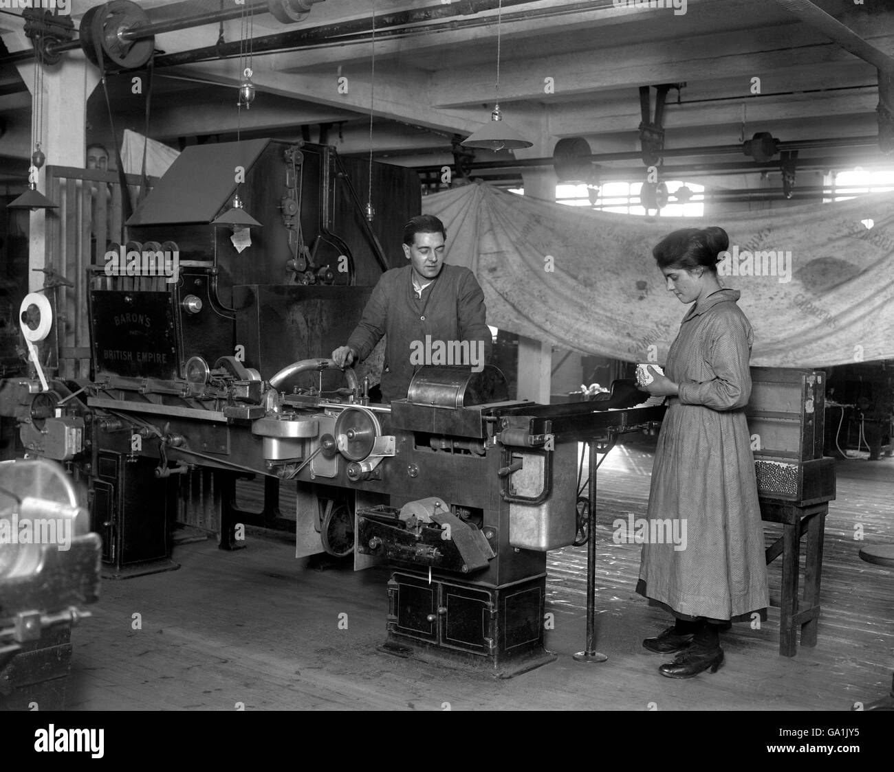 Eine Maschine, die billiger Rauch erzeugen kann. Ein Mädchen, das mit einer gewöhnlichen Zigarettenmaschine arbeitet, die monatlich 7,000,000 Zigaretten oder 650 Zigaretten pro Minute in den Herren Carreras Arcadia produziert, arbeitet an der City Road in London. Stockfoto