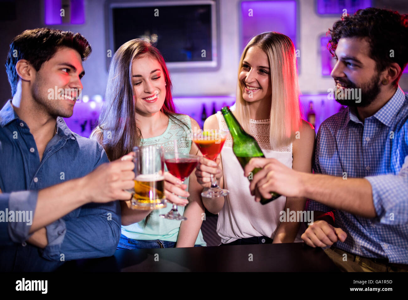 Gruppe von Freunden Toasten cocktail, Bierflasche und Bierglas am Tresen Stockfoto