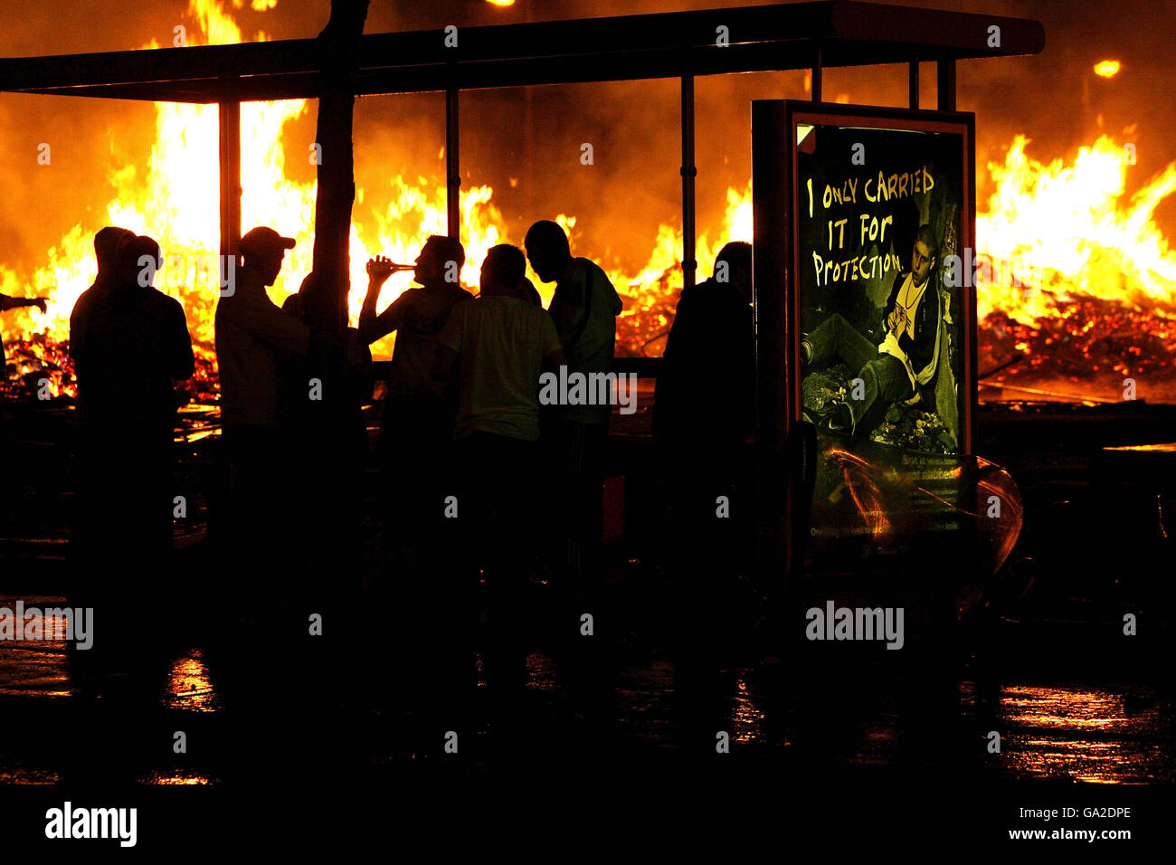 Protestantische Jugendliche beobachten ein Lagerfeuer auf der Shankil Road in Belfast. Stockfoto