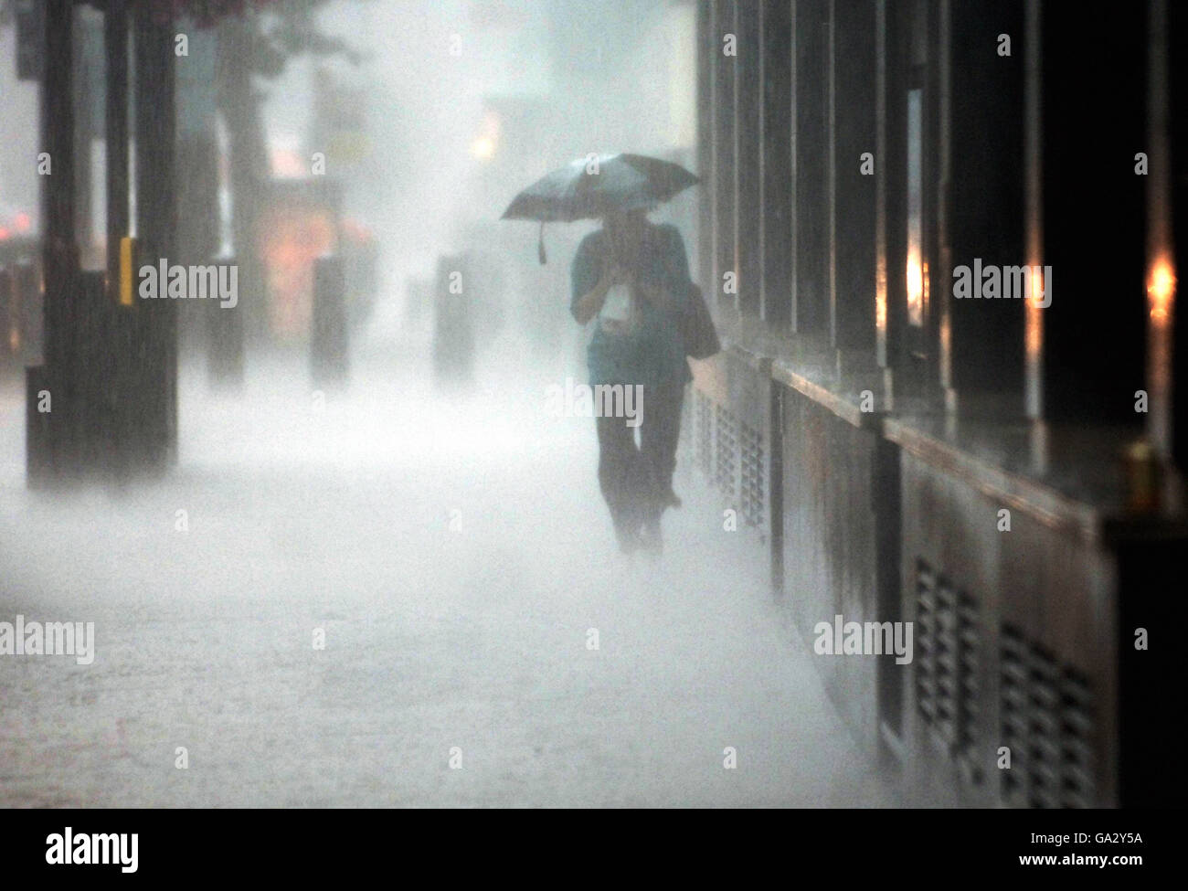 Eine Dame trotzt dem sintflutartigen Regen, der heute im Zentrum Londons fiel. Stockfoto