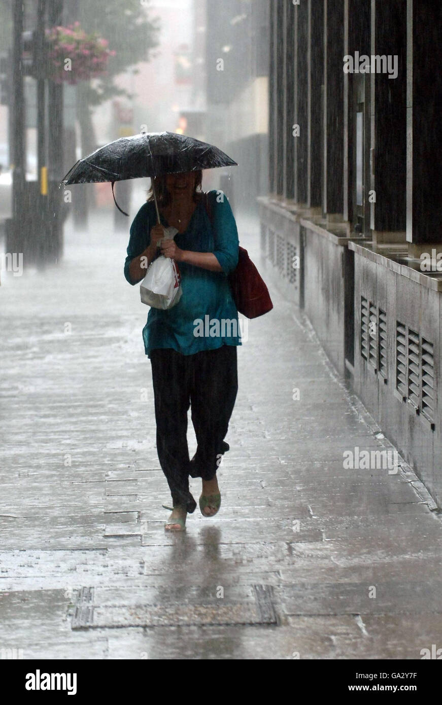 Eine Dame trotzt dem sintflutartigen Regen, der heute im Zentrum Londons fiel. Stockfoto
