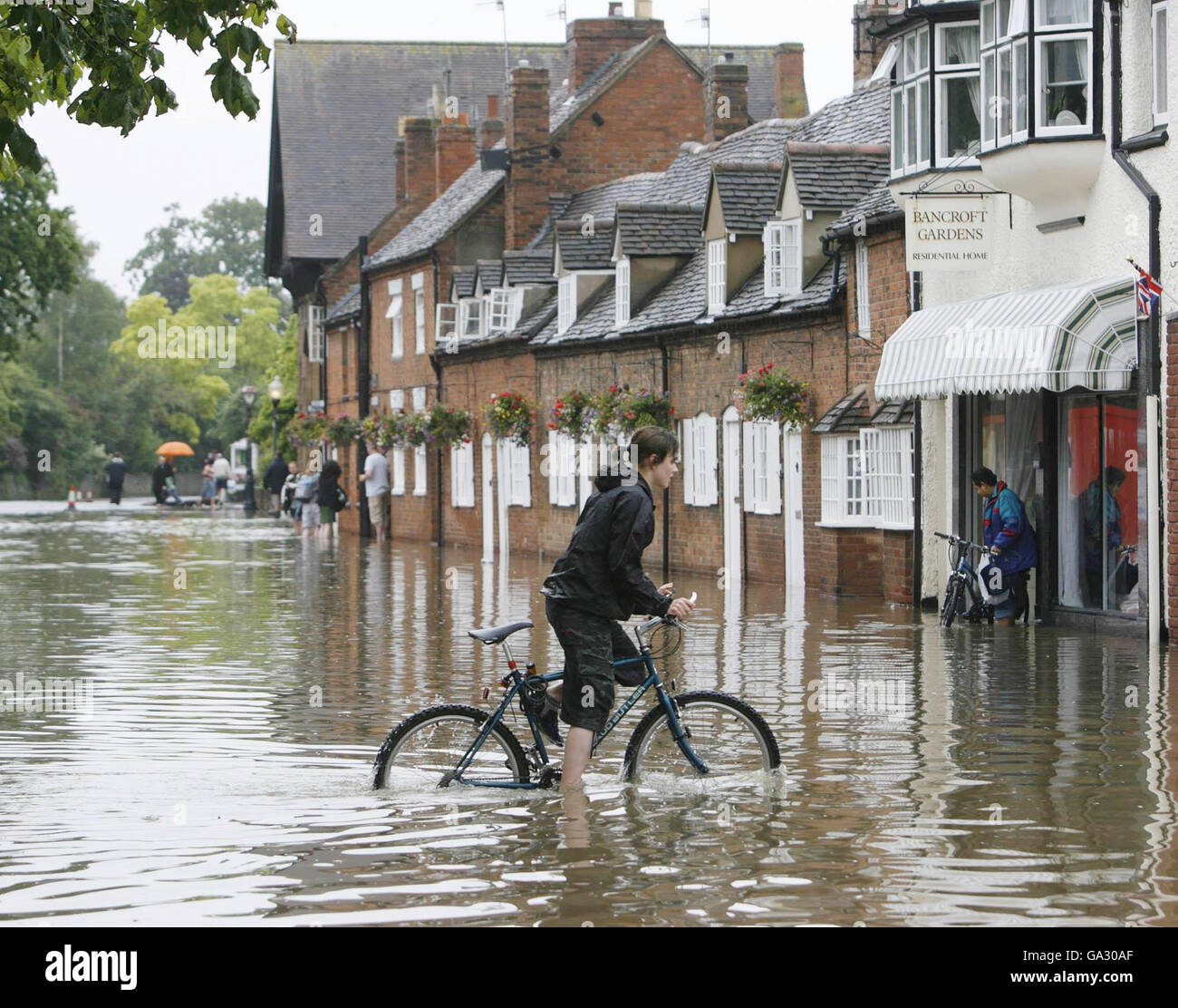 Eine Radfahrerin macht sich auf den Weg über eine Straße in Straford-upon-Avon in Warwickshire, nachdem mehrere Teile Großbritanniens nach einem Tag starken Regens von Überschwemmungen heimgesucht wurden. Stockfoto
