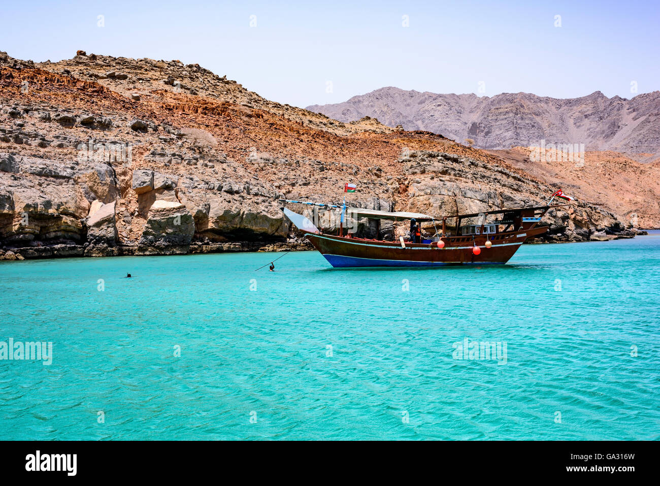 Traditionelle arabische Dhow, die im fjordähnlichen Musandam festmacht, mit touristischem Schnorcheln rund um und an Bord, Sultanat Oman Stockfoto