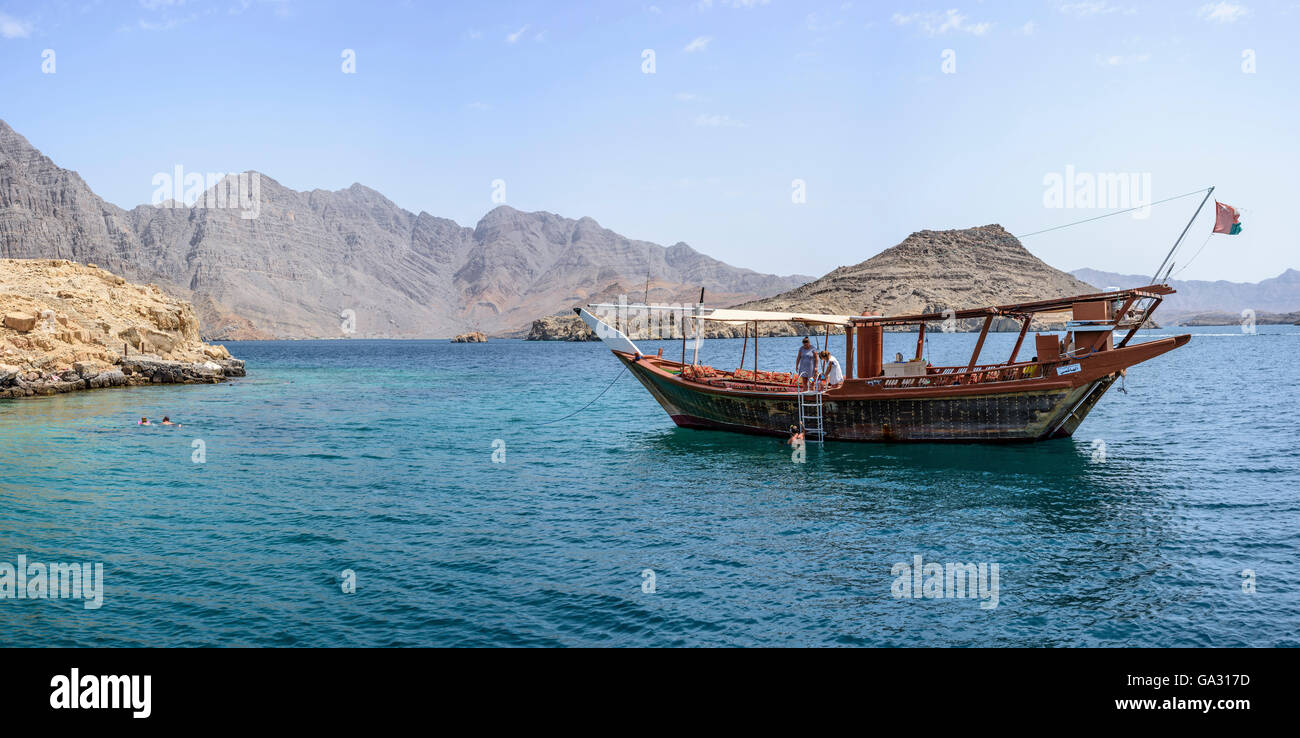 Traditionelle arabische Dhow-Anlegestelle im Fjord in Musandam mit touristischem Schnorcheln rund um das Boot, Sultanat von Oman Stockfoto