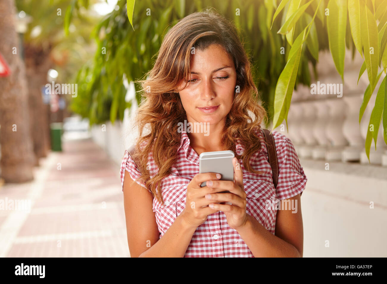 Taille bis Porträt einer schönen Frau mit mittellangen Haaren mit einem Smartphone für SMS Stockfoto