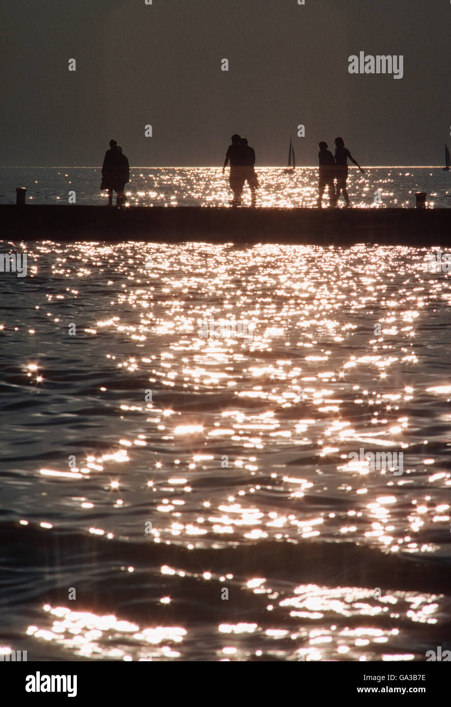 Urlauber, die Silhouette gegen Reflexionen der untergehende Sonne am Lake Michigan; Michigan; USA Stockfoto