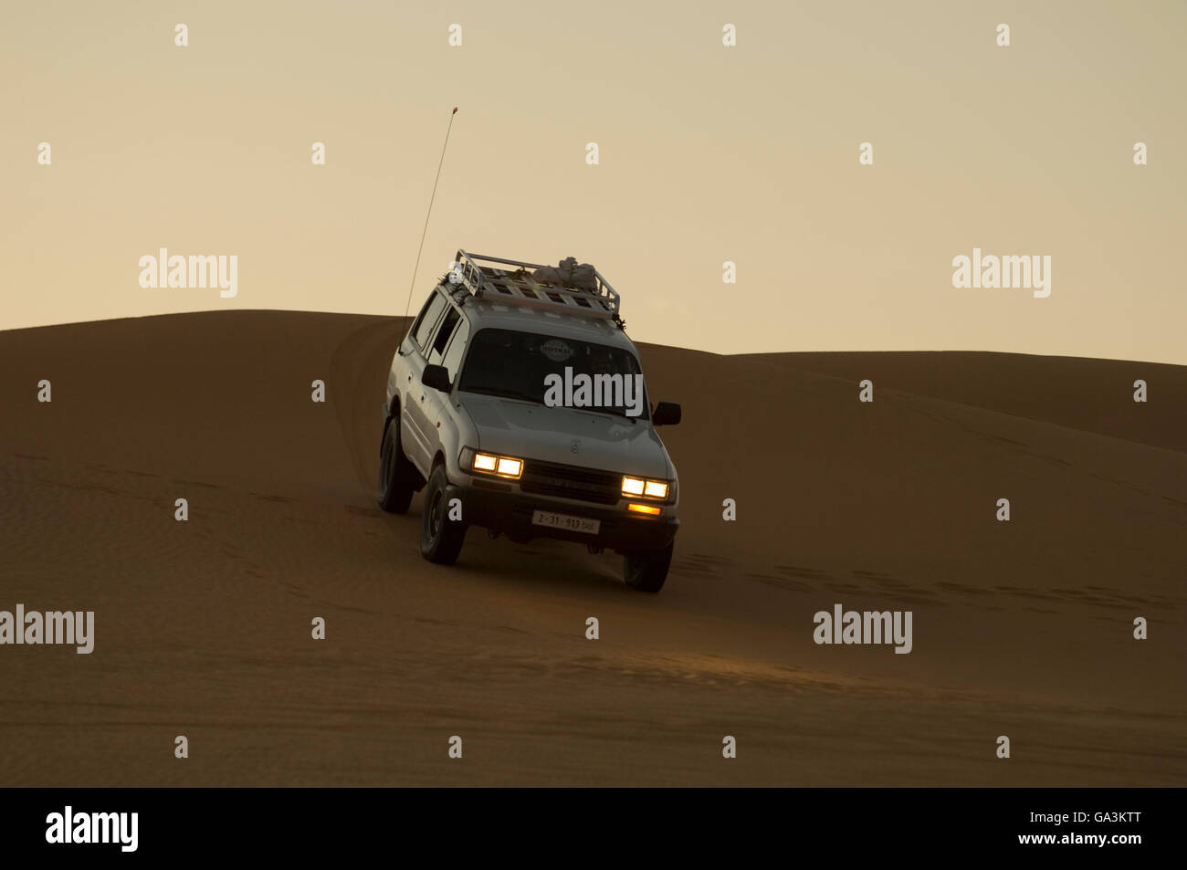 SUV auf Sanddünen bei Dämmerung, Erg Awbari, Sahara Wüste, Fezzan, Libyen, Nordafrika Stockfoto