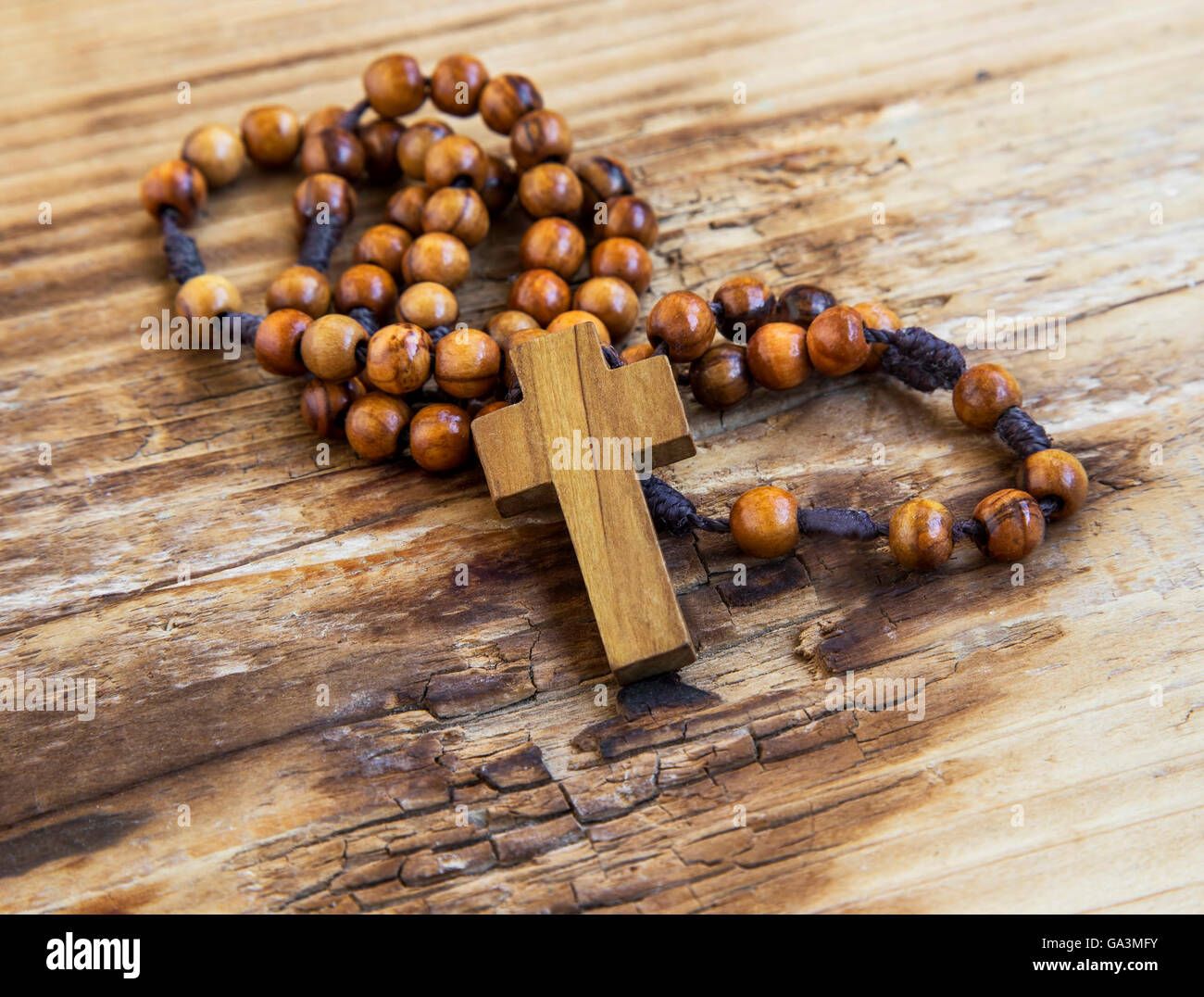 Holzkreuz mit Rosenkranz. Das Christentum Symbol auf hölzernen Hintergrund Stockfoto