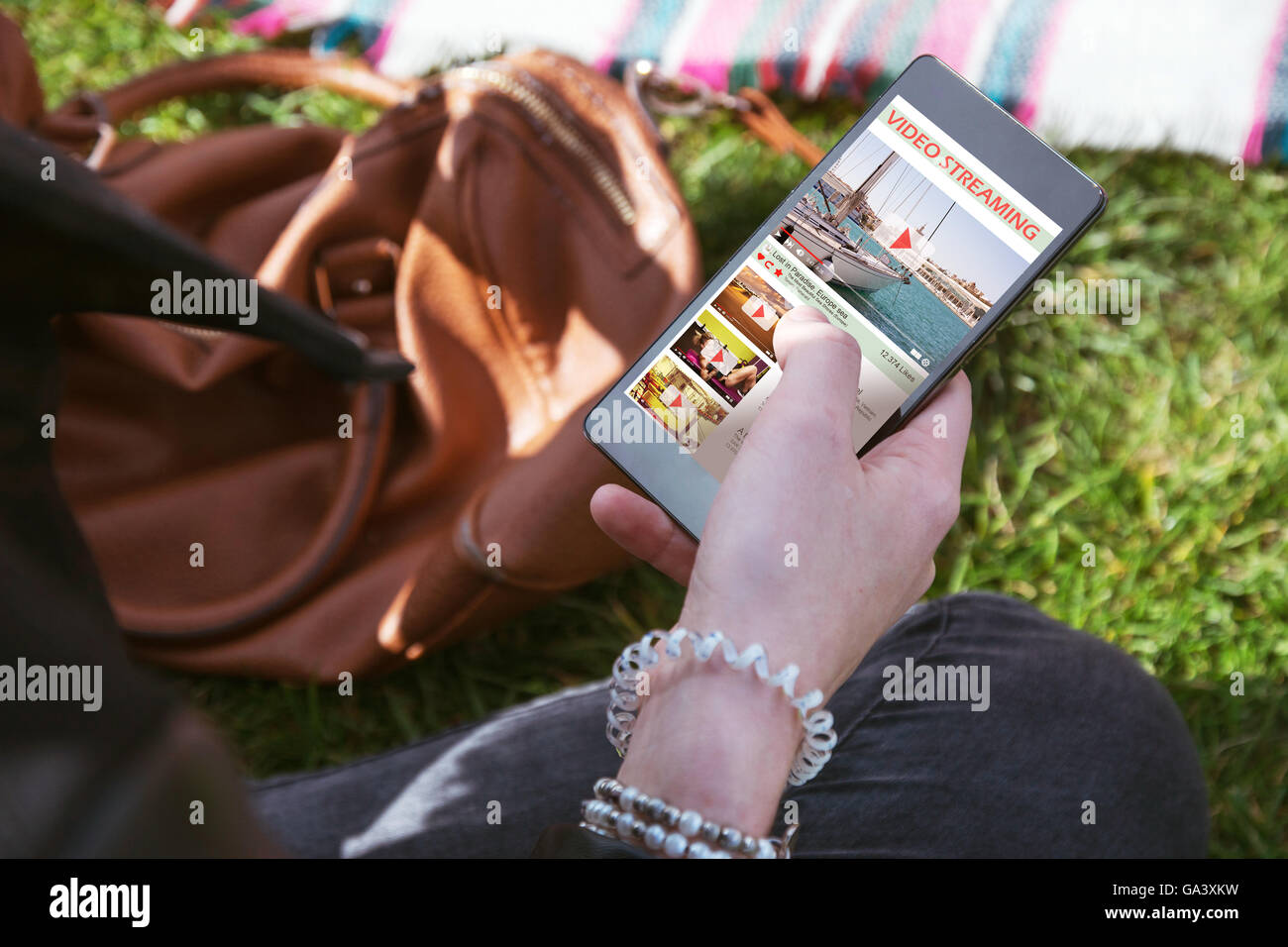 Frau-Touchscreen-Smartphone mit video-streaming, im park Stockfoto