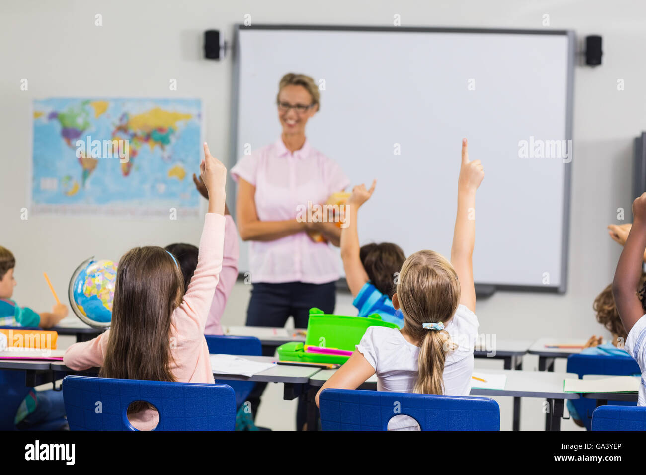 Schülerinnen und Schüler mit Hände hoch während der Lektion Stockfoto