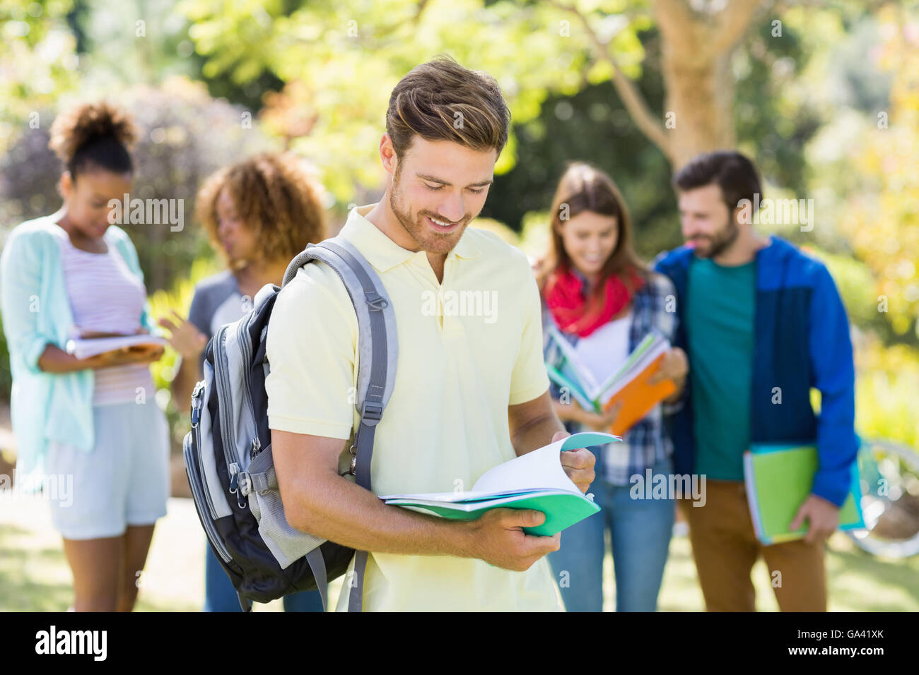 Junge College Notenlesen mit Freunden im Hintergrund Stockfoto