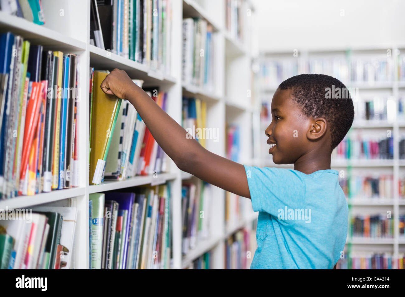 Schuljunge Bücherregal in der Bibliothek ein Buch auswählen Stockfoto
