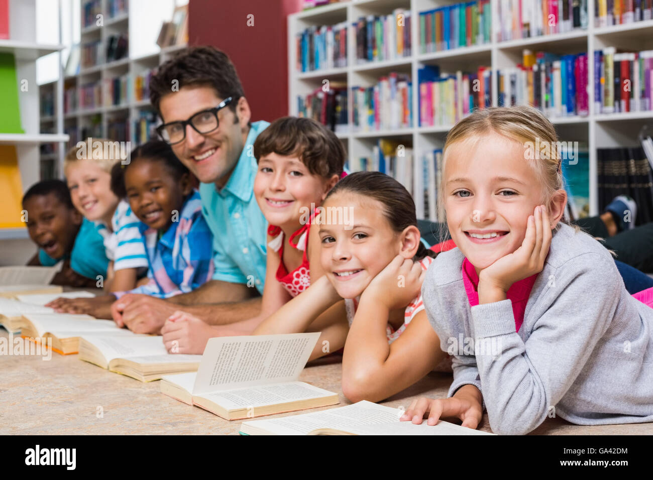 Lehrer und Kinder lesen Buch in Bibliothek Stockfoto
