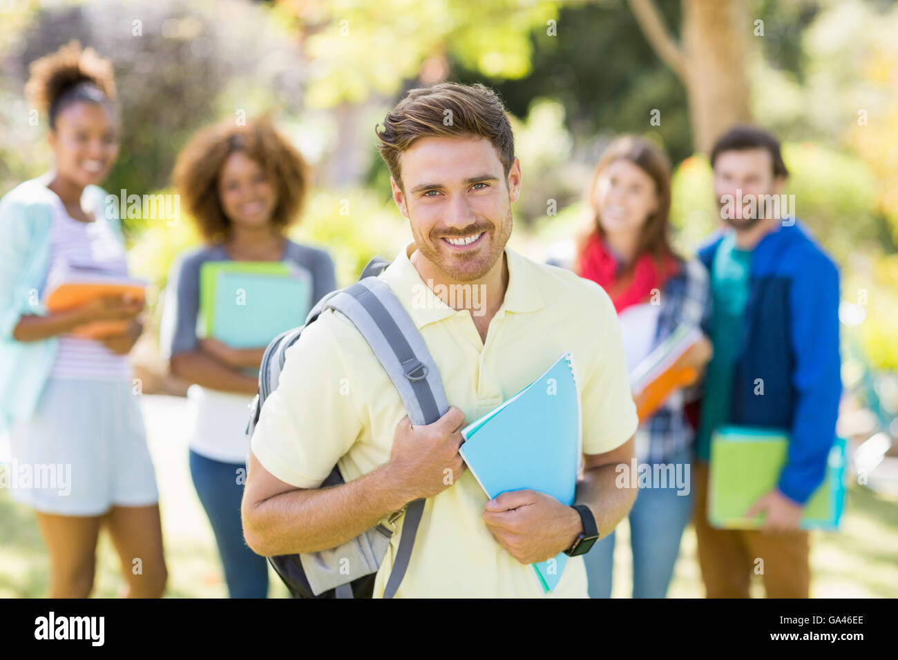 Portrait von junge College halten Notizen mit Freunden im Hintergrund Stockfoto