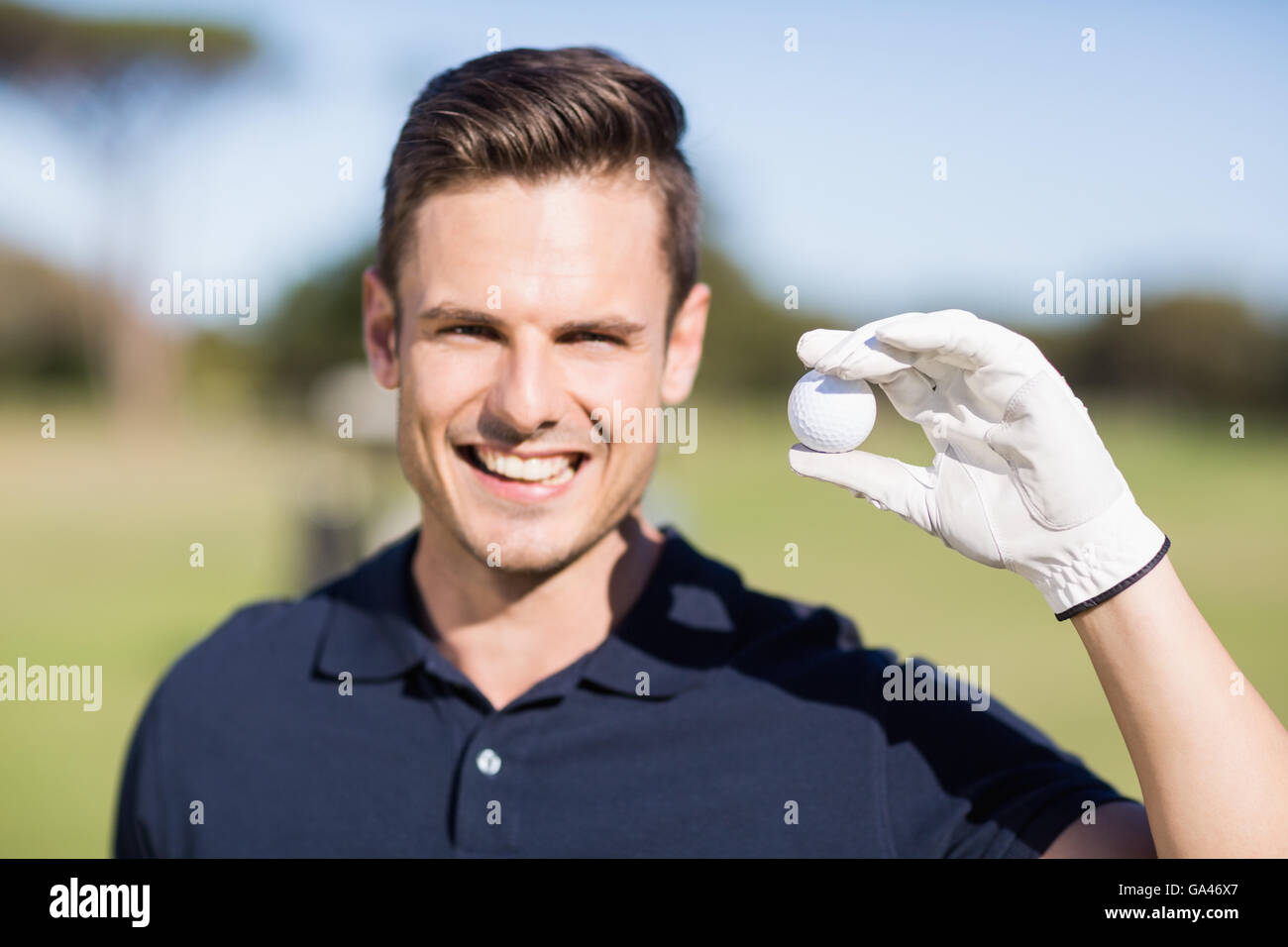 Porträt von fröhlichen jungen Mann zeigt Golfball Stockfoto